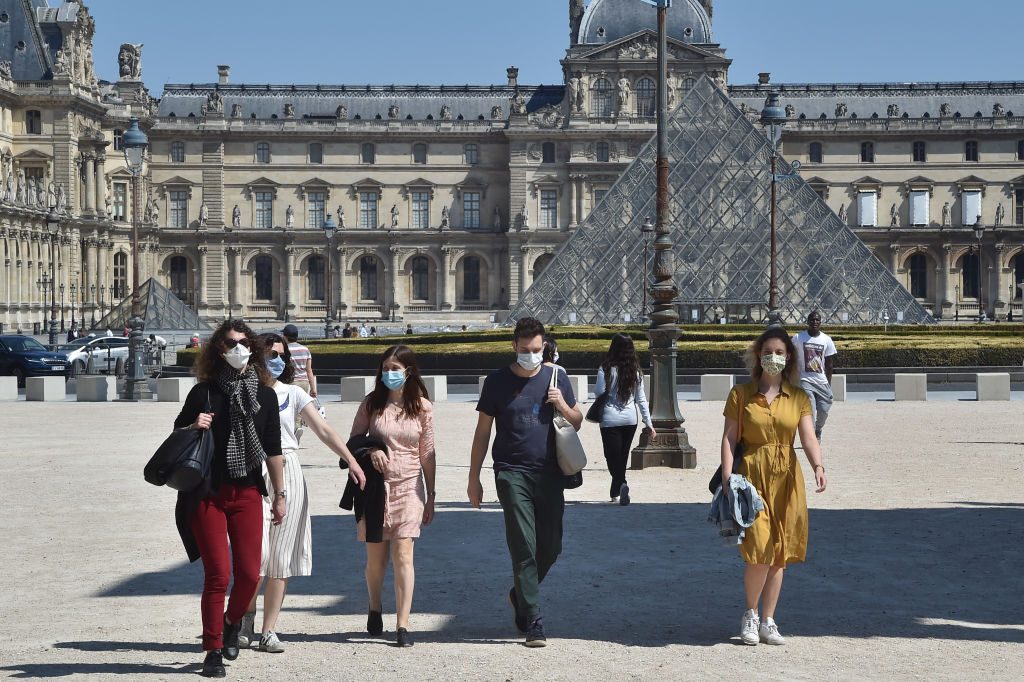 People wearing protective face masks outside the Louvre in Paris. Photo by Stephane Cardinale - Corbis/Corbis via Getty Images.
