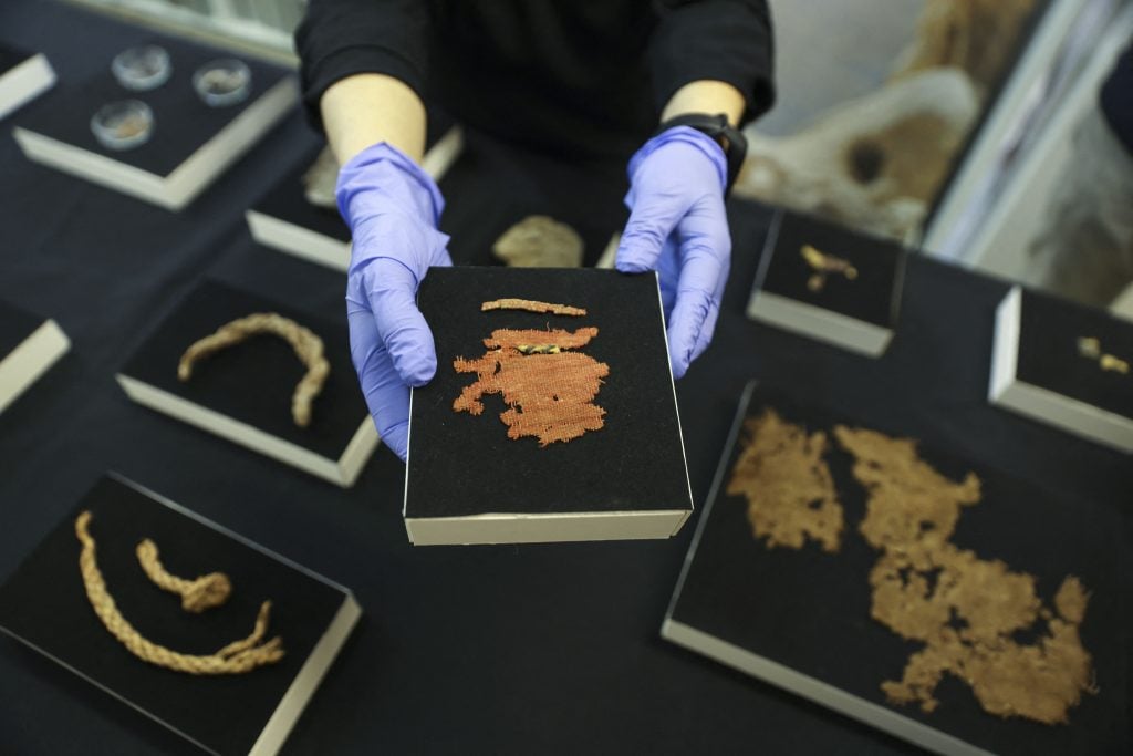 An archaeologist at the Israel Antiquities Authority shows a cloth fragment from the Bar Kochba Jewish revolt period, excavated from an area in the Judean Desert, after conservation work is done at the IAA's Dead Sea conservation laboratory in Jerusalem. Photo by Menahem Kahana/AFP via Getty Images.
