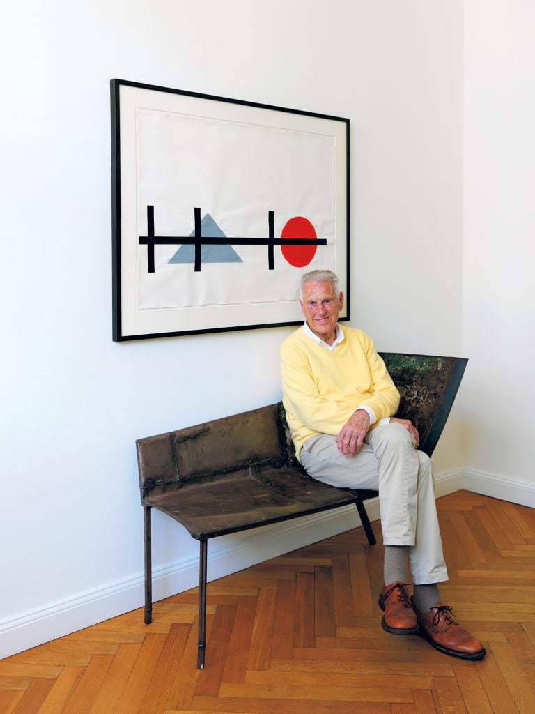 Rudolf Zwirner, seated on Franz West’s Liege (Doppelsitz) (1989) under the work Berlin Series (1979) by Gary Kuehn, in his home in Berlin, 2020. Courtesy David Zwirner.