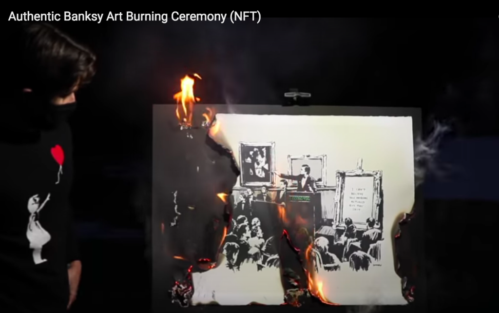 A masked man sets a Banksy work alight in a video on YouTube.