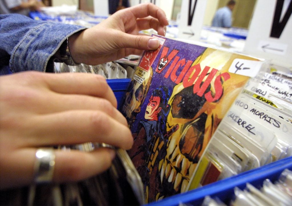 Collectors browse though bins of comic books July 6, 2001 at the Big Apple Comic Book, Art, and Toy Show in New York City. Photo by Mario Tama/Getty Images.