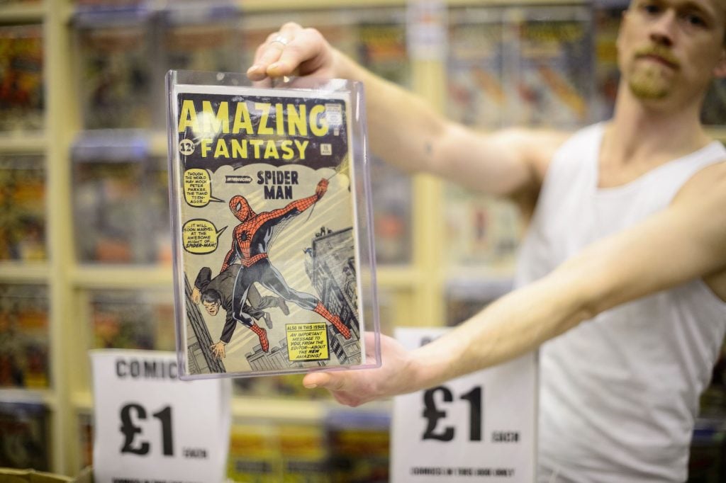A stallholder holds up a copy of the first comicbook to feature Spiderman at the London Film and Comic Con 2014 in Earls Court. Photo be Leon Neal/AFP via Getty Images.