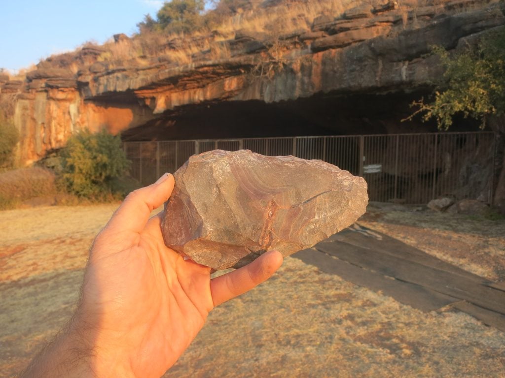 A hand axe from Wonderwerk Cave, seen in front of the cave entrance. Photo courtesy of Michael Chazan.