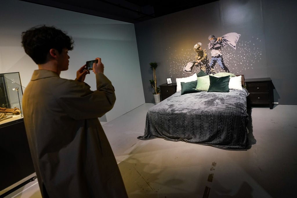 A visitor takes a photo of a recreation of The Walled Off Hotel room at the "Banksy: Genius or Vandal?" exhibition at Asobuild on March 27, 2020 in Yokohama, Japan. (Photo by Christopher Jue/Getty Images)