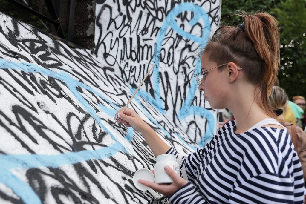 Volunteers restore an artwork by Russian calligrapher Pokras Lampas (Arseny Pyzhenkov) in a public garden by the Drama Theatre. Photo by Donat Sorokin/TASS via Getty Images.