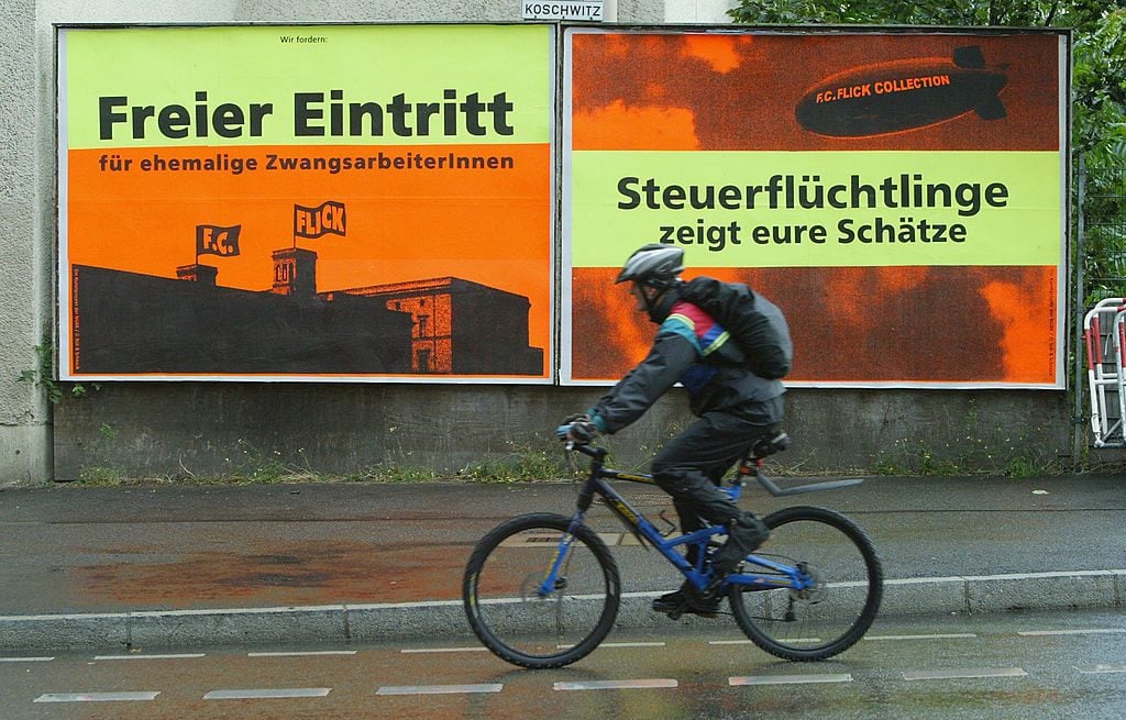 A cyclist rides by two billboards put up by local artists to protest against the nearby Christian Friedrich Flick Collection at the Hamburger Bahnhof Museum in 2004 in Berlin. The signs say 