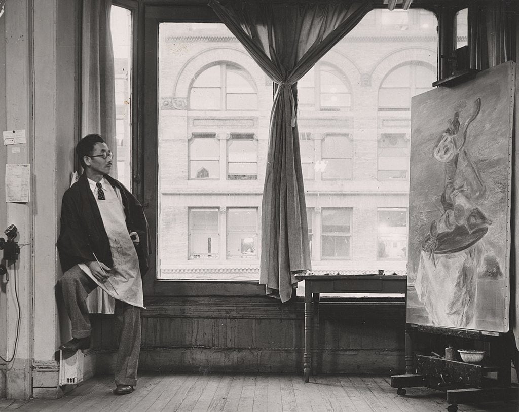 Kuniyoshi working on his painting "Upside Down Table and Mask" in his studio near Union Square at 30 East Fourteenth Street in New York City. Photo by Max Yavno, courtesy the Archives of American Art.