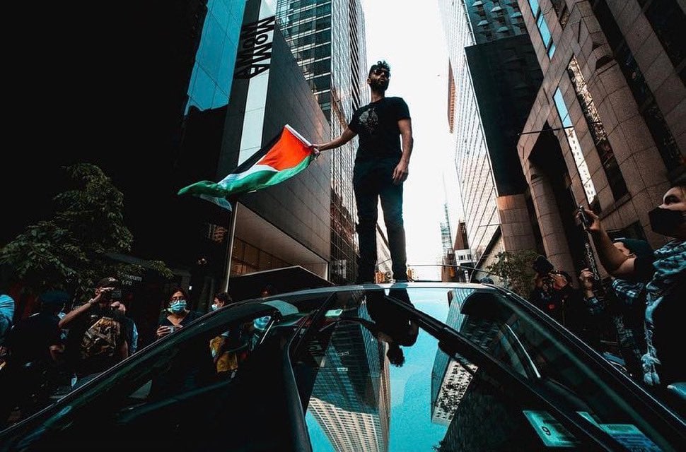 A demonstrator holding a Palestinian flag during a recent Strike MoMA protest. Courtesy of Strike MoMA via Twitter.