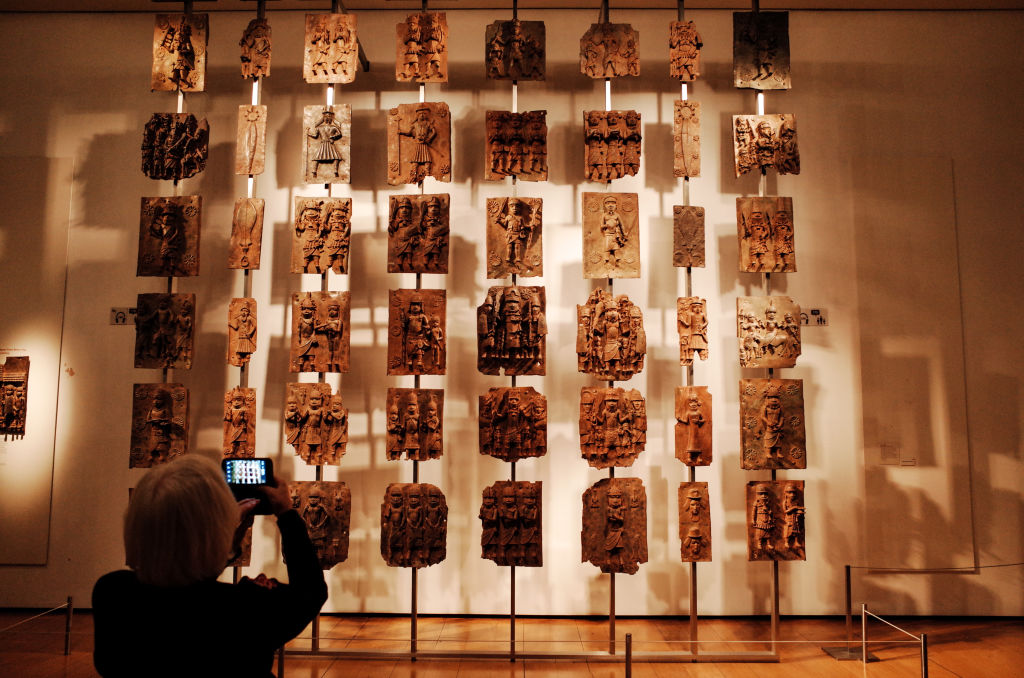 A visitor takes photos of the contentious Benin plaques exhibit (more commonly known as the Benin bronzes) at the British Museum in London. Photo by David Cliff/SOPA Images/LightRocket via Getty Images.