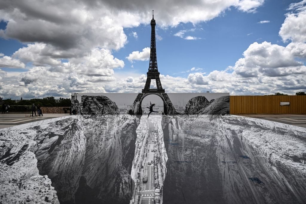 A giant artwork by French street artist and photographer Jean Rene, aka JR, on display at the Eiffel Tower. Photo by Anne-Christine Poujoulat / AFP via Getty Images.