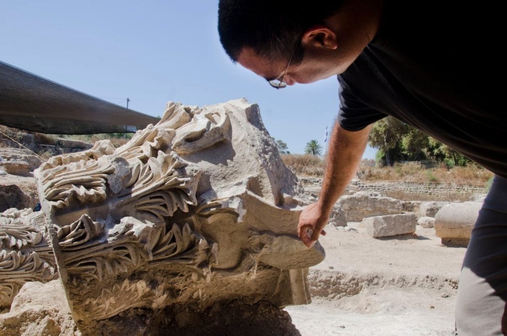 Archaeologist Saar Ganor with a capital in Tel Ashkelon National Park. Photo by Yoli Shwartz courtesy of the Israel Antiquities Authority.