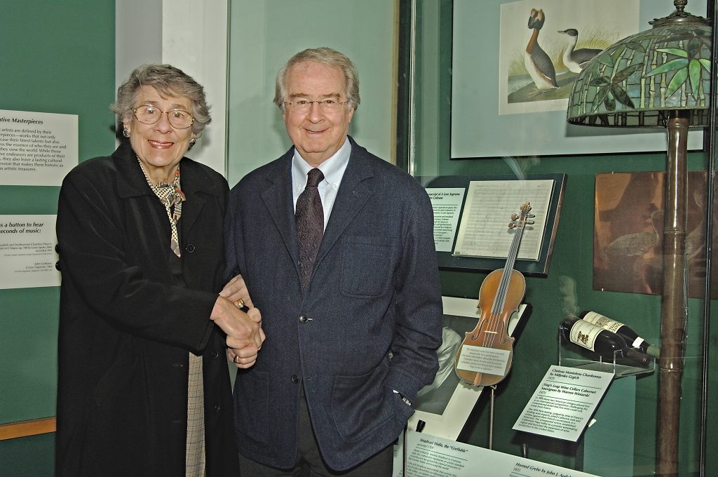 Barbara and Warren Winiarski, founders of Stag's Leap Wine Cellars, posing in front of a display of the 1976 Judgment of Paris winning wines in 2008. Photo by Richard Strauss, courtesy of the Smithsonian's National Museum of American History.