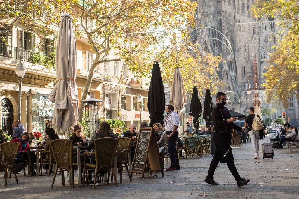 La gente cena fuera de un restaurante frente a La Sacrada Familia en Barcelona.  (Foto de Diego Prudencio / Sofa Images / Lightrocket a través de Getty Images)