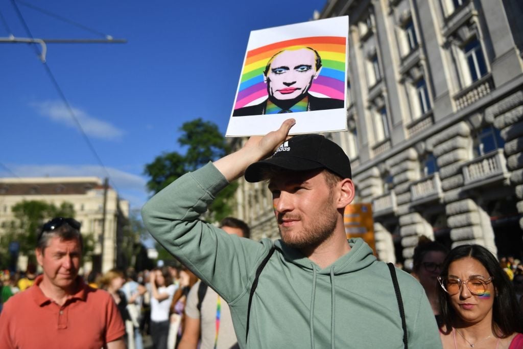 A participant holds a placard showing Russian President Vladimir Putin, in front of the parliament building in Budapest on June 14, 2021, during a demonstration against the Hungarian government's draft bill seeking to ban the 