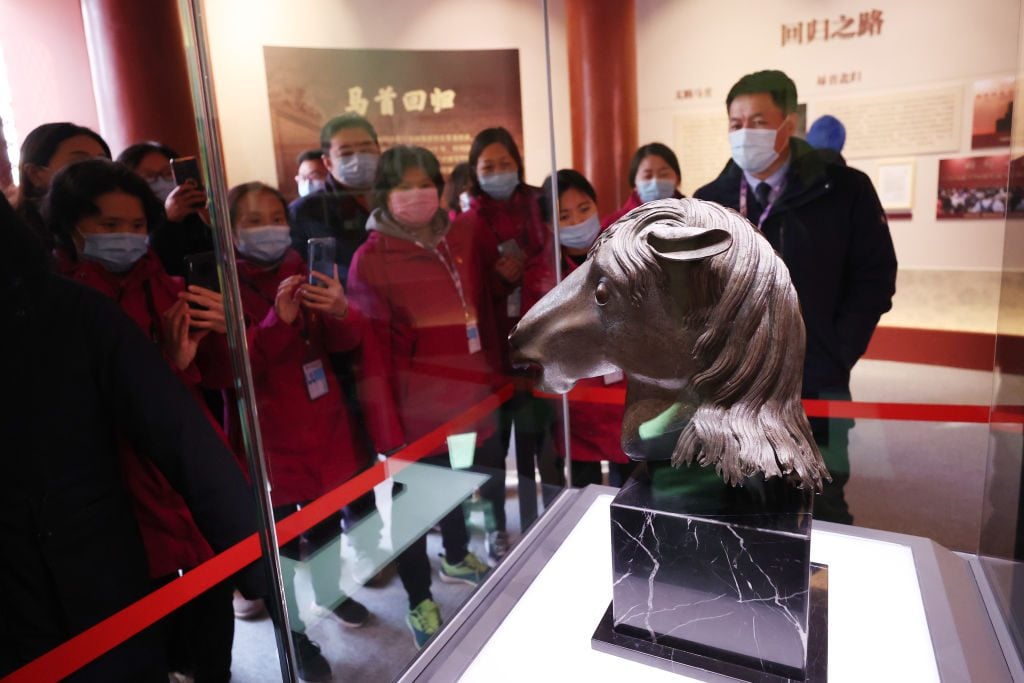 Visitors watch a bronze statue of a horse's head exhibited at the Zhengjue Temple in the Old Summer Palace (Yuanmingyuan). Photo by Chen Xiaogen/VCG via Getty Images)