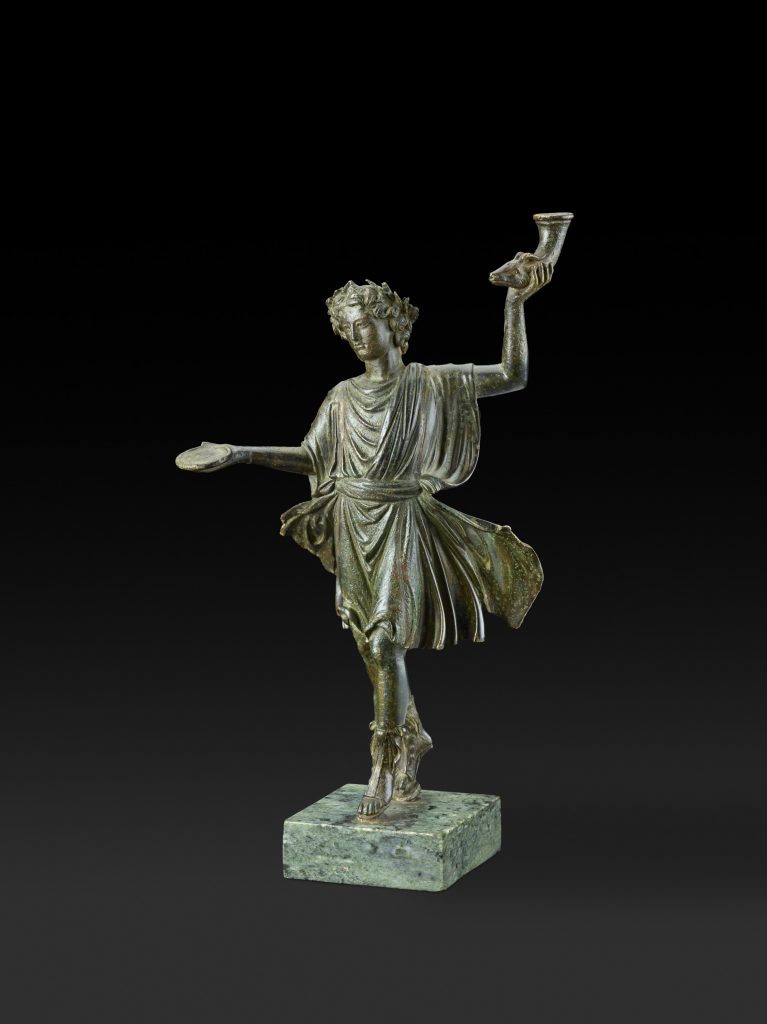 Statuette of a Lar (household deity) holding a <em>rhyton</em> (drinking vessel) and libation dish (AD 1–100). Photo courtesy of the Ashmolean Museum of Art and Archaeology and the Fine Arts Museums of San Francisco