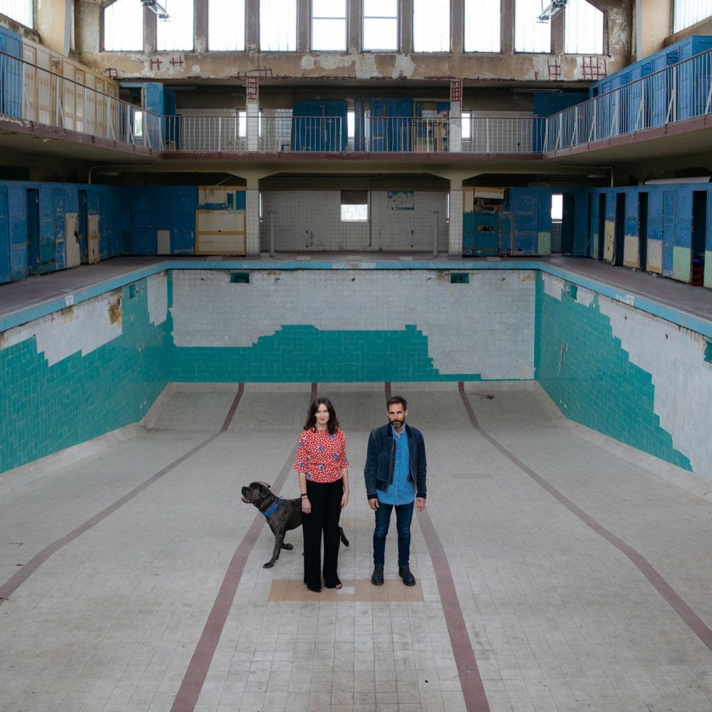 Co-Artistic Directors, Helen Turner and Pablo Wendel with their dog Coal in the Bauhaus swimming hall, which will be the location of the <i>Sea & Sun</i> performances in Berlin this weekend. © Lukas Korschan for The FACE.