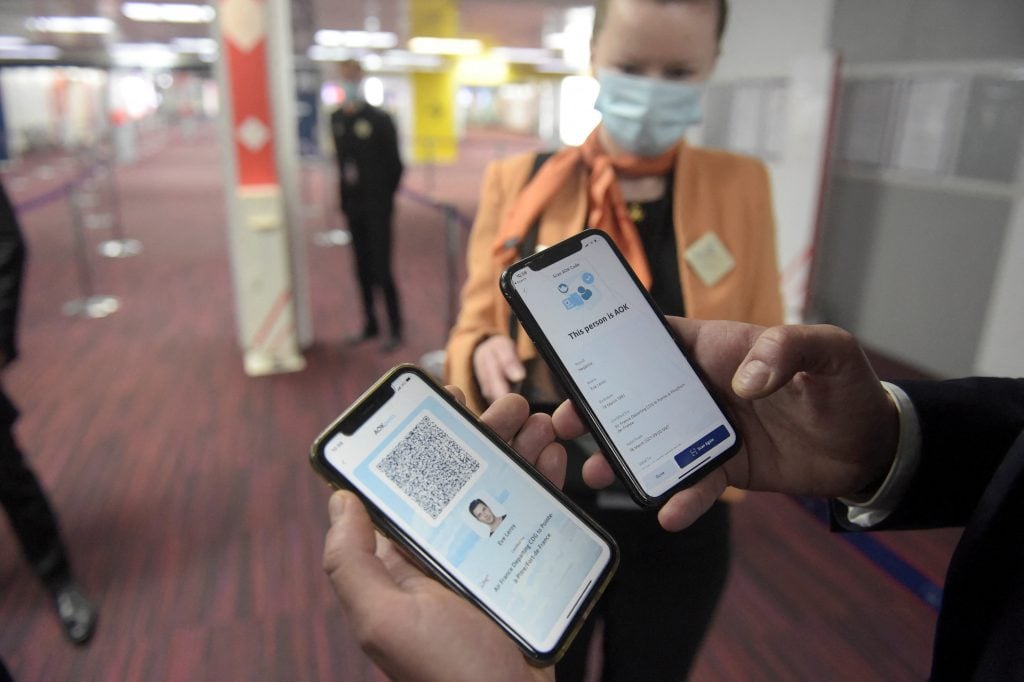 A man displays smartphones showing the AOK pass app at the arrivals area of Roissy-Charles de Gaulle airport on March 18, 2021, during a trial stage of Air France's digital sanitary pass "AOKpass". - The ICC AOKpass is a mobile app, available on smartphones and allowing passengers to carry a secure record of the results of their COVID-19 test. Photo by Eric Piermont/AFP via Getty Images.