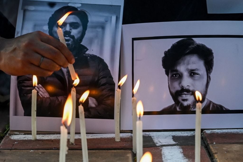 Candles by journalists next to the portrait of Reuters journalist Danish Siddiqui. Photo by DIBYANGSHU SARKAR/AFP via Getty Images.
