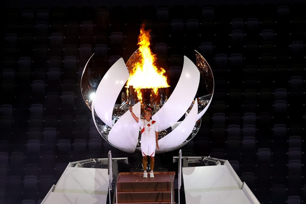 Naomi Osaka of Team Japan holds up the Olympic torch after lighting the Olympic cauldron during the Opening Ceremony of the Tokyo 2020 Olympic Games at Olympic Stadium. Photo by Laurence Griffiths/Getty Images.