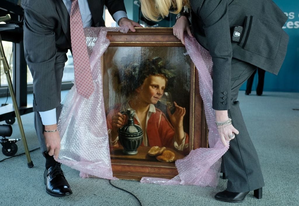 Federal Bureau of Investigation (FBI) agents unwrap Young Man As Bacchus by Jan Franse Verzijl for a ceremony at the Museum of Jewish Heritage in New York on February 8, 2017, to formally return the painting to representatives of the Max and Iris Stern Foundation. Photo: Jewel Samad/AFP via Getty Images.