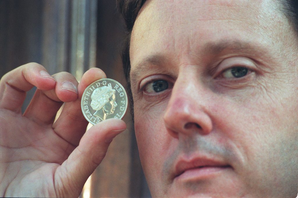 Medallist and sculptor Ian Rank-Broadley, in London holding a coin bearing the his portrait of the Queen. Courtsey of Getty Images.