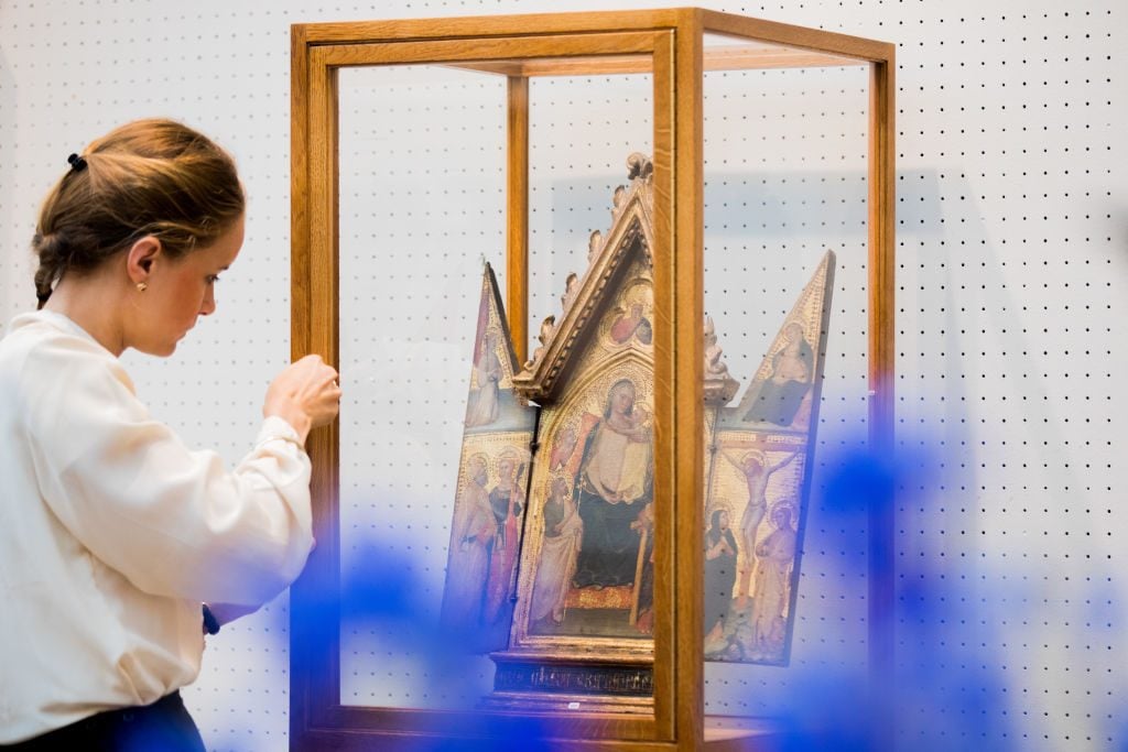 Employee Donata Richtsteig standing in front of a folding altar with an enthroned Madonna (Meister des Tobias) from the estate of Cardinal Meisner. at Kunsthaus Lempertz in 2018. Photo: Rolf Vennenbernd/picture alliance via Getty Images.