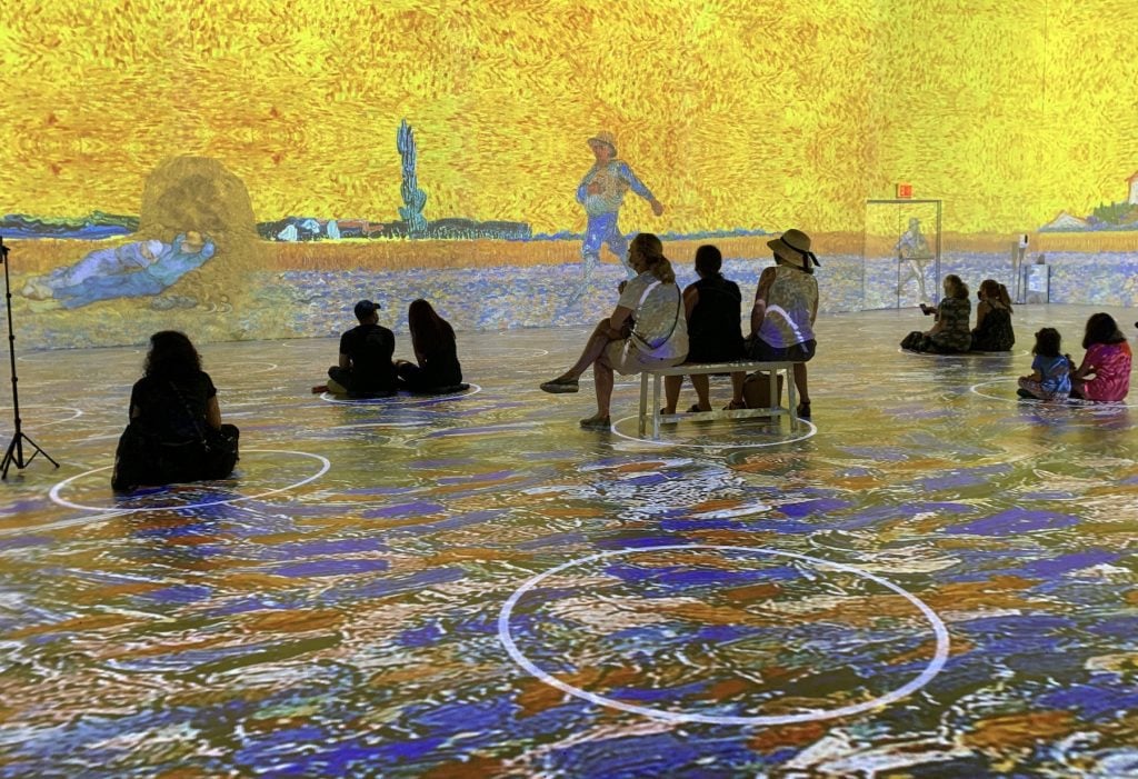 Visitors contemplate a projection of a Van Gogh landscape along a large wall in Immersive Van Gogh. Photo by Ben Davis.