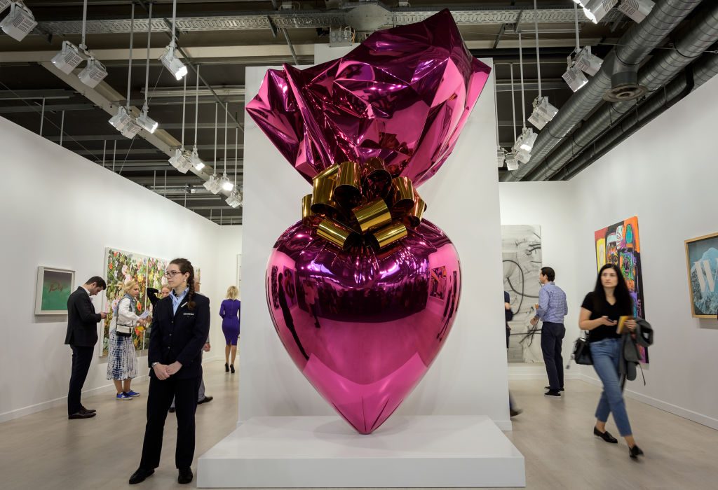 Visitors stand next to an artwork by Jeff Koons at the Gagosian gallery . Photo: Farbice Coffrini/AFP. via Getty Images.