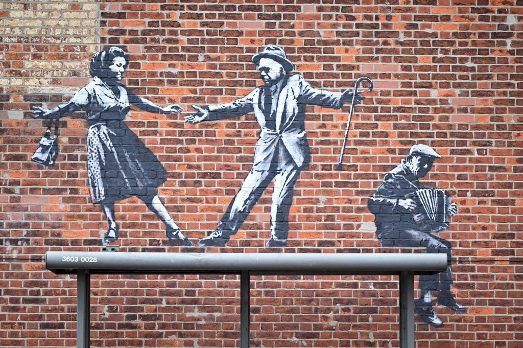 A graffiti artwork of a couple dancing to an accordion player in Great Yarmouth is one of several possible new Banksy works on the East coast of England. Photo by Justin Tallis/AFP via Getty Images.