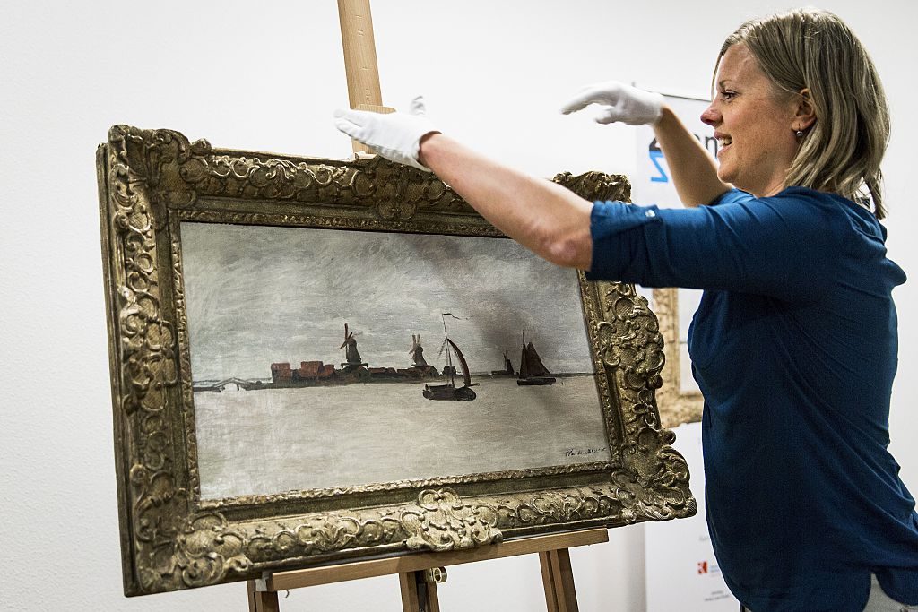 A Zaans Museum employee presents the museum's new purchase, <i>The Voorzaan and Westerhem</i> by Claude Monet, in Zaandam on June 2, 2015. Photo: Valerie Kuypers/AFP via Getty Images.