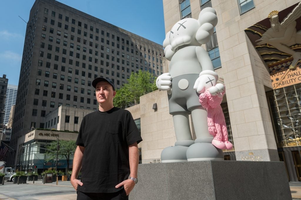 The artist Brian Donnelly, better known as KAWS, unveils his new sculpture SHARE at Rockefeller Center in New York. The 18-foot-tall bronze figure features two of the artist's iconic motifs, 