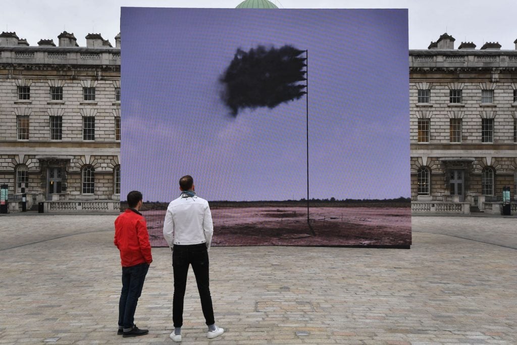 People pose with a work of art by Irish artist John Gerrard entitled Western Flag at Somerset House in central London on April 21, 2017. Photo by Ben Stansall/AFP via Getty Images.