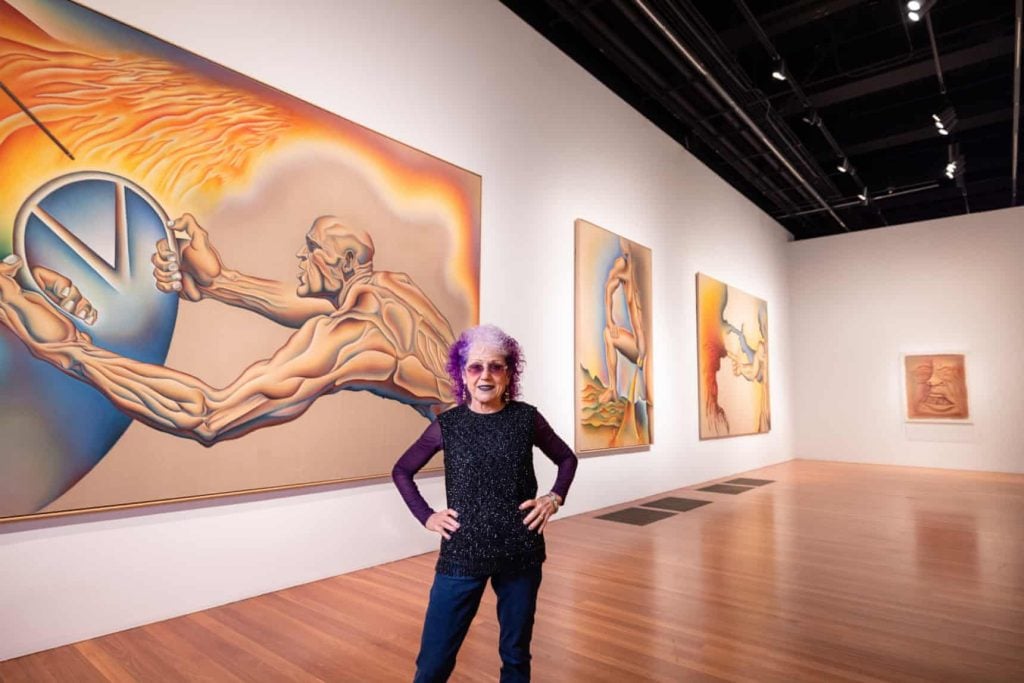 Judy Chicago with paintings from her "Power Play" series in her retrospective at the de Young Museum, San Francisco. Photo by Gary Sexton, courtesy the de Young Museum, San Francisco.