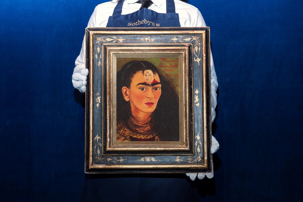 An art handler holds Frida Kahlo's 1949 painting Diego y yo (Diego and I). Courtesy of Sotheby's.