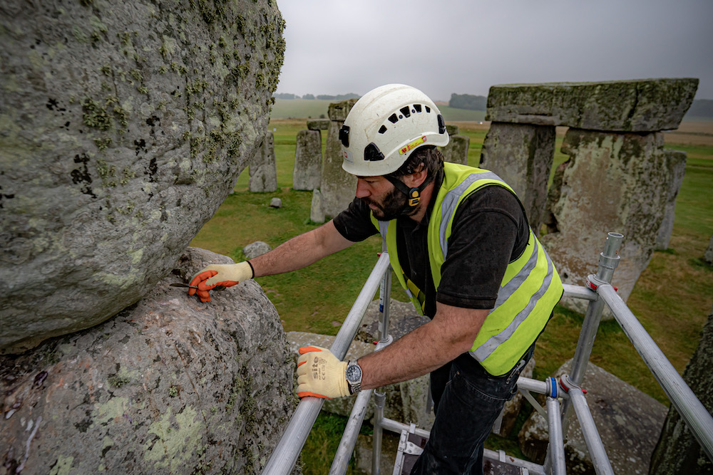 Conservator James Preston uses a pointing spoon atop scaffold erected inside the stone circle at Stonehenge as specialist contractors from SSH Conservation repair defects from previous repairs, carried out the 1950's, on a trilithon in the stone circle and carry out vital conservation work at Stonehenge, Wiltshire. Picture date: Tuesday September 14, 2021. (Photo by Ben Birchall/PA Images via Getty Images)