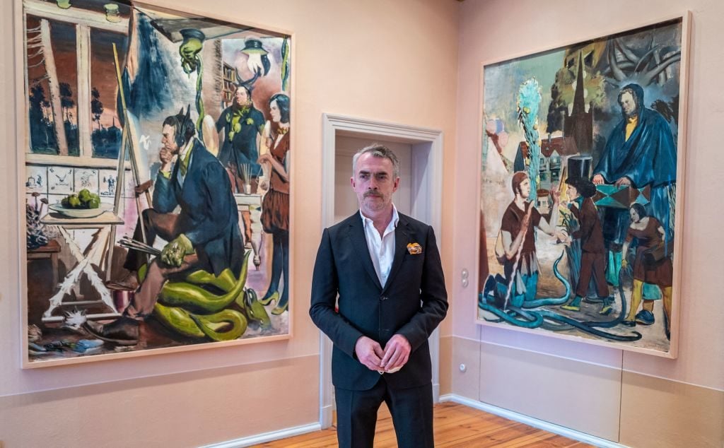 German painter Neo Rauch poses in front of his paintings Die Erwartung and Die Wegzehr during a preview of his exhibition 