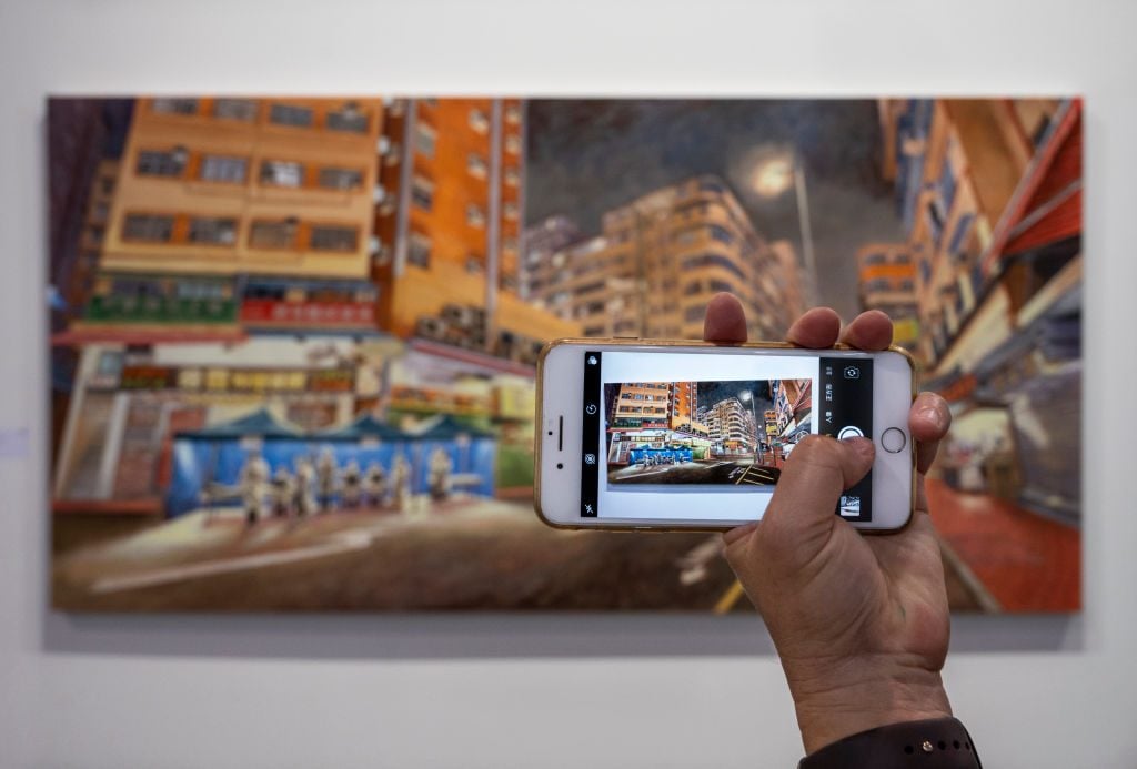 A visitor takes a photo of a painting at Art Basel Hong Kong in May 2021. (Photo by Miguel Candela/SOPA Images/LightRocket via Getty Images)