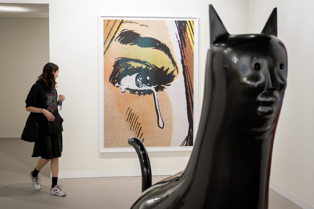 A visitor looks at an artwork by Anne Collier entitled Woman Crying (Comic) #7 at Art Basel on June 12, 2019. (Photo by Fabrice Coffrini/AFP via Getty Images.)