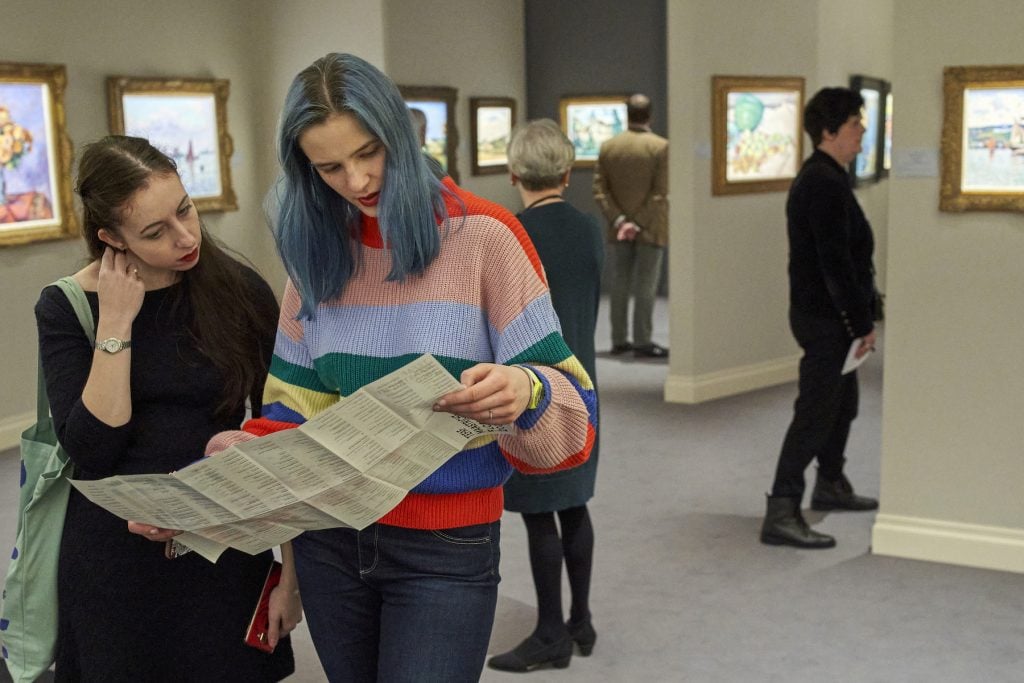 Two of the visitors look at a map with the location of the art galleries during the TEFAF art fair on March 7, 2020 in Maastricht, Netherlands. (Photo courtesy Getty Images.)