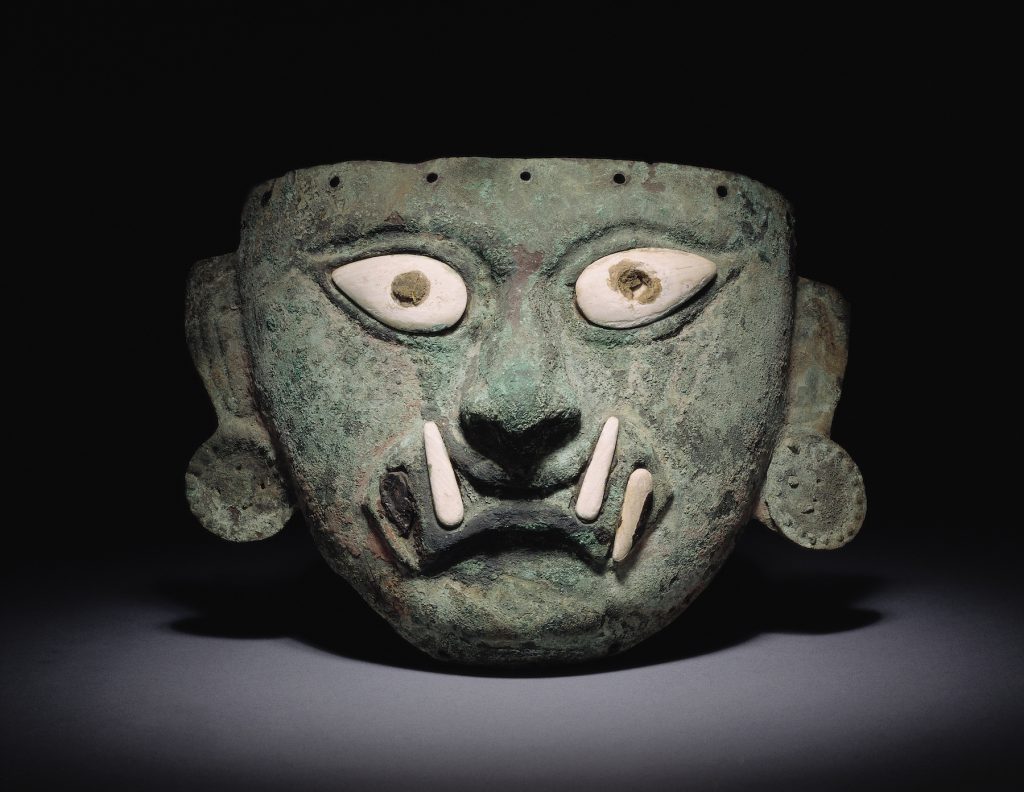 Ai Apaec, copper funerary mask with applications of shell and stone, depicting an anthropomorphic visage with feline fangs (ca. 1 AD –800 AD). Collection of the Museo Larco, Lima, Peru. Photo courtesy of World Heritage Exhibitions.