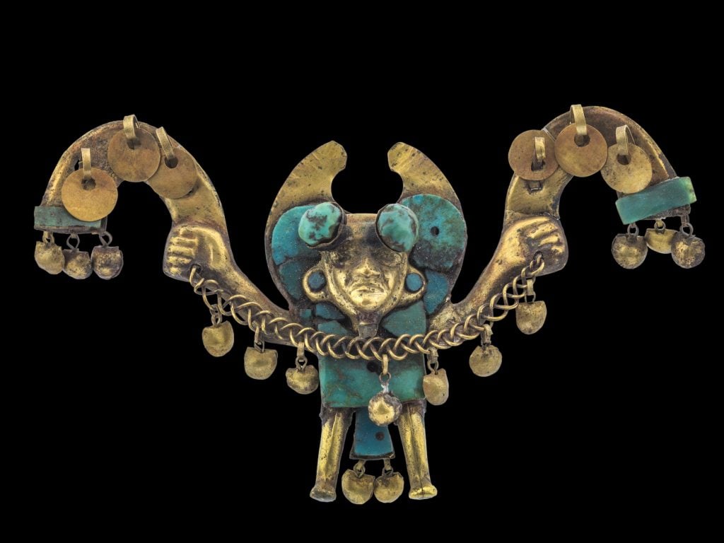 Gold and turquoise nose ornament depicting figure with half-moon and club-head headdress, circular ear ornaments and loincloth, holding a rattle (ca. 1 AD–800 AD). Collection of the Museo Larco, Lima, Peru. Photo courtesy of World Heritage Exhibitions.