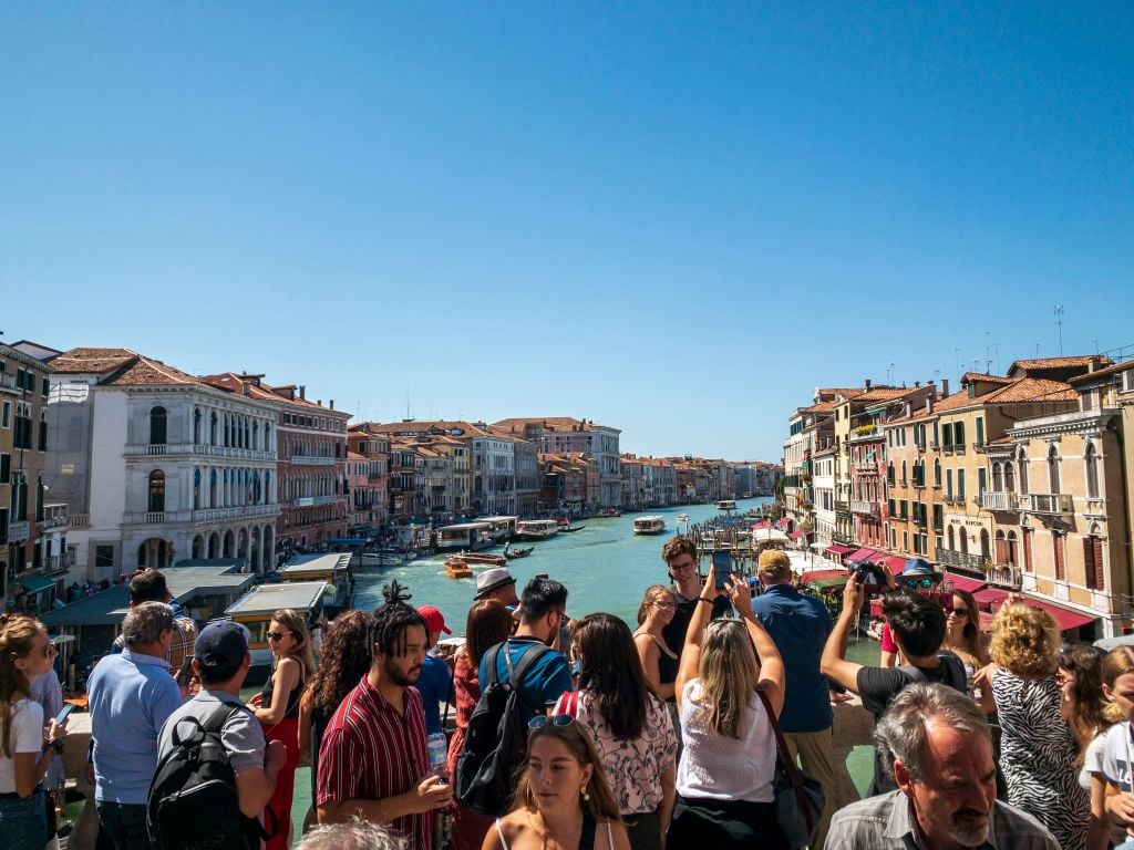 Rialto Bridge overlooking the Grand Canal with crowds of tourists, Venice, Italy. (Photo by: Jumping Rocks/Education Images/Universal Images Group via Getty Images)