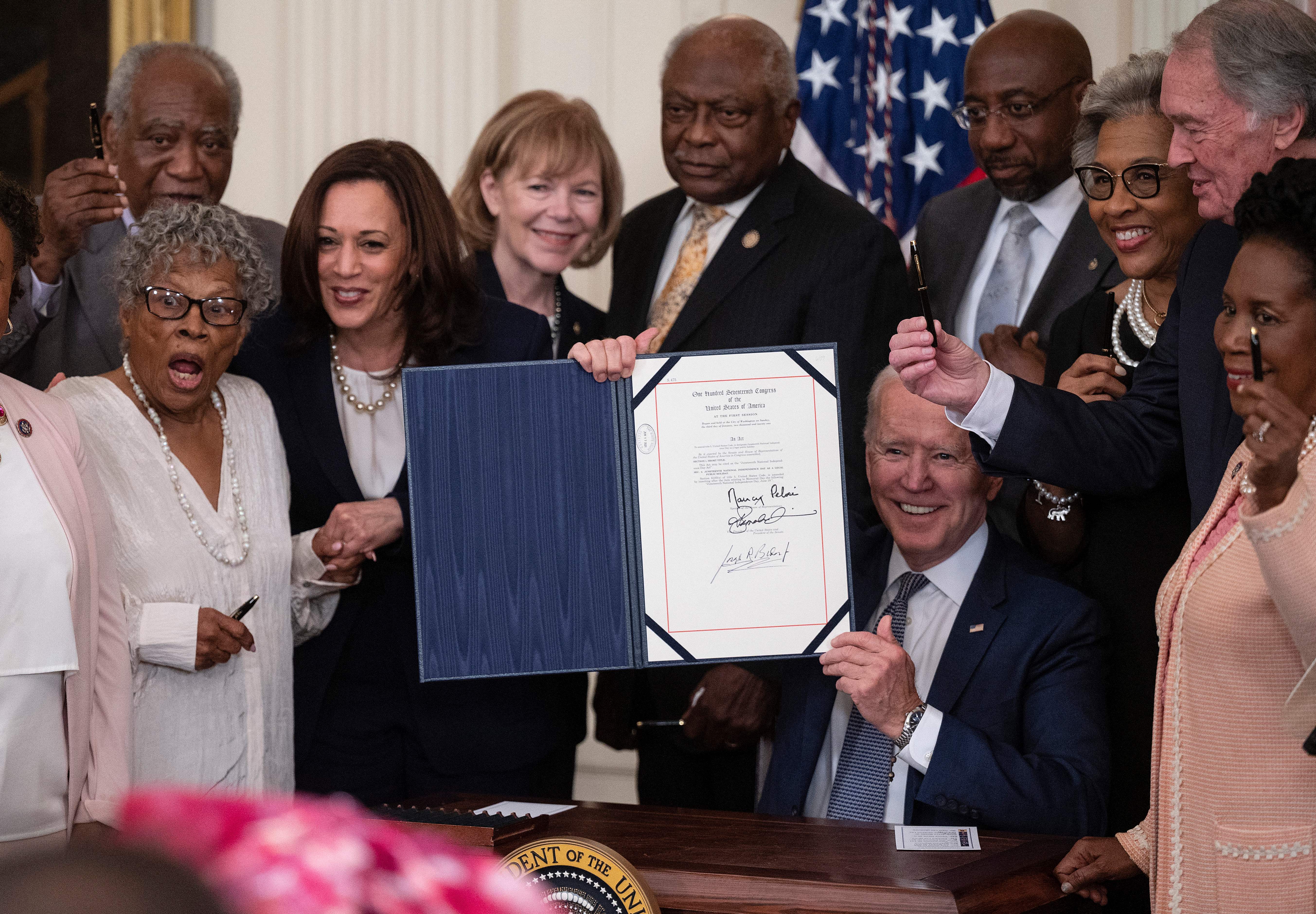 US Vice President Kamala Harris and Opal Lee (2nd L), the activist known as the Grandmother of Juneteenth, watch as President Joe Biden holds the signed Juneteenth National Independence Day Act, in the East Room of the White House, June 17, 2021, in Washington. Photo by Jim Watson/AFP via Getty Images.