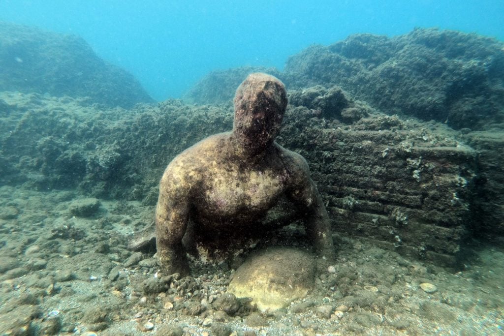 A copy of an original statue, preserved at the Museum of Baiae, of Baios offering a cup of wine to Polyphemus, in the Nymphaeum of punta Epitaffio, in the submerged ancient Roman city of Baia at the Underwater Archaeological Park of Baia, part of the Campi Flegrei Archaeological Park complex site in Pozzuoli near Naples. Photo by Andreas Solaro/AFP via Getty Images.