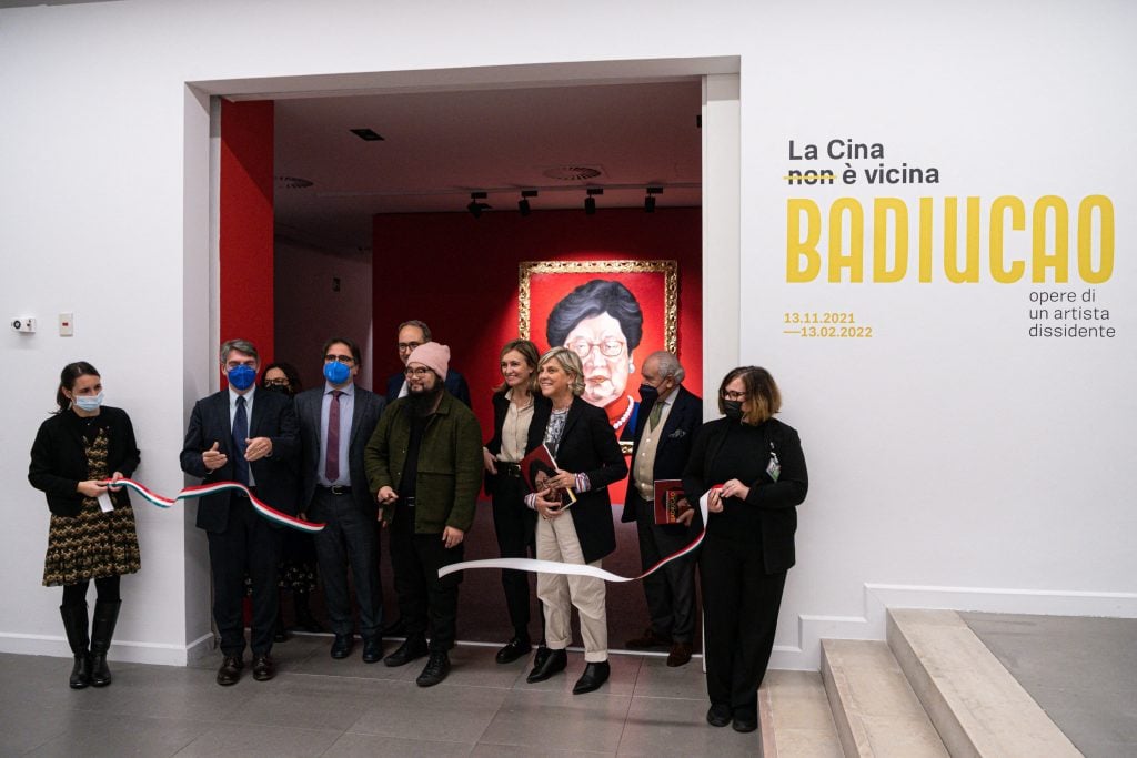 Chinese dissident artist Badiucao (C), with Mayor of Brescia, Emilio Del Bono (2ndL), vice-Mayor of Brescis, Laura Castelletti (3rdR), President of Fondazione Brescia Musei, Francesca Bazoli (4thR), cuts the ribbon on the opening of an exhibition of his artworks on November 12, 2021 entitled "China is (not) near -- works of a dissident artist", at the Santa Giulia museum in Brescia, Lombardy. Photo by Piero Cruciatti/AFP via Getty Images.