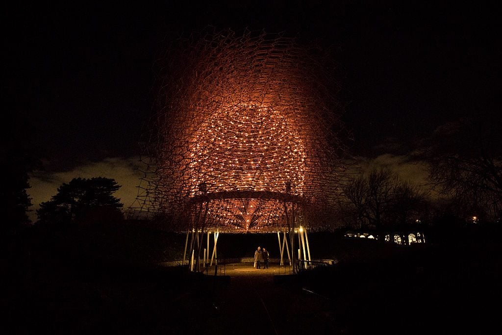 A couple stands underneath Wolfgang Buttress' illuminated <i>Hive</i> Installation at Kew Gardens in London, England. Photo: Jack Taylor/Getty Images.