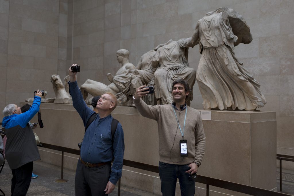 Visitors pose in front of the British Museum's Parthenon Marbles in 2017. Photo by Richard Baker / In Pictures via Getty Images Image.