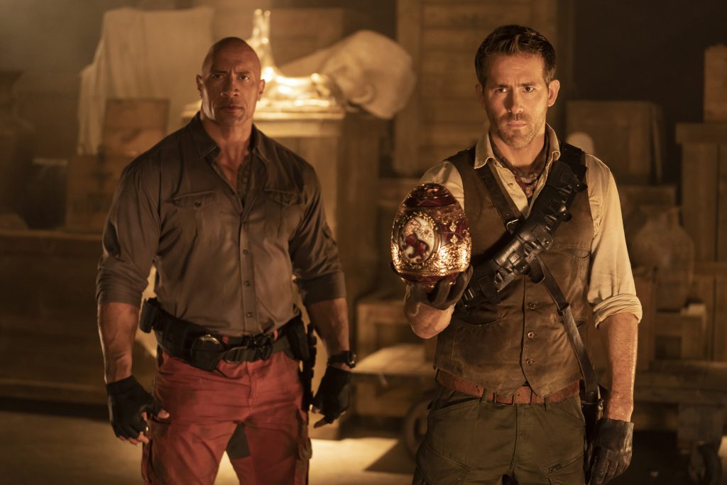 Dwayne Johnson as John Hartley and Ryan Reynolds as Nolan Booth with one of Cleopatra's Eggs in Netflix's <em>Red Notice</em>. Photo by Frank Masi, courtesy of Netflix ©2021.