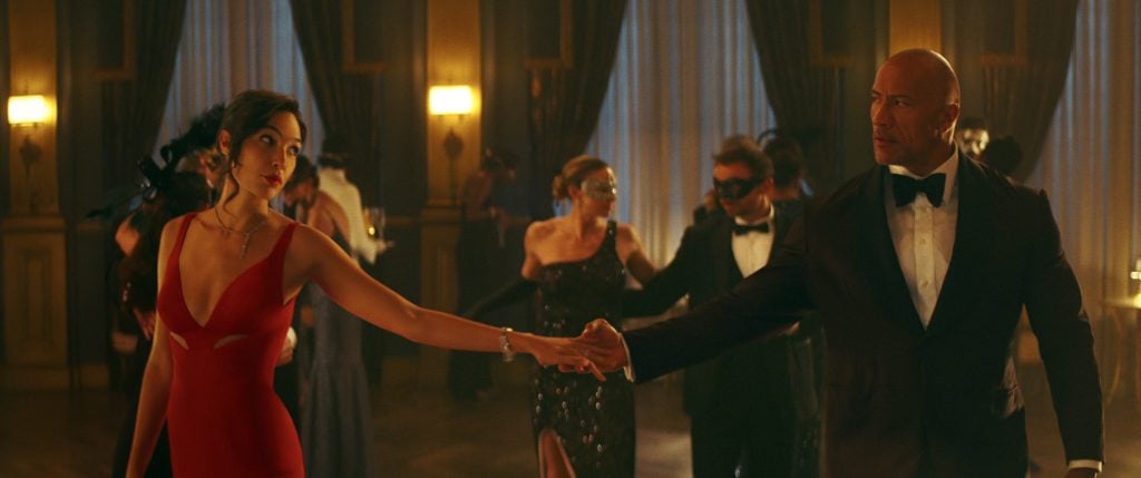 Gal Gadot and Dwayne Johnson dance in Netflix's <em>Red Notice</em>. Photo by Frank Masi, courtesy of Netflix ©2021.